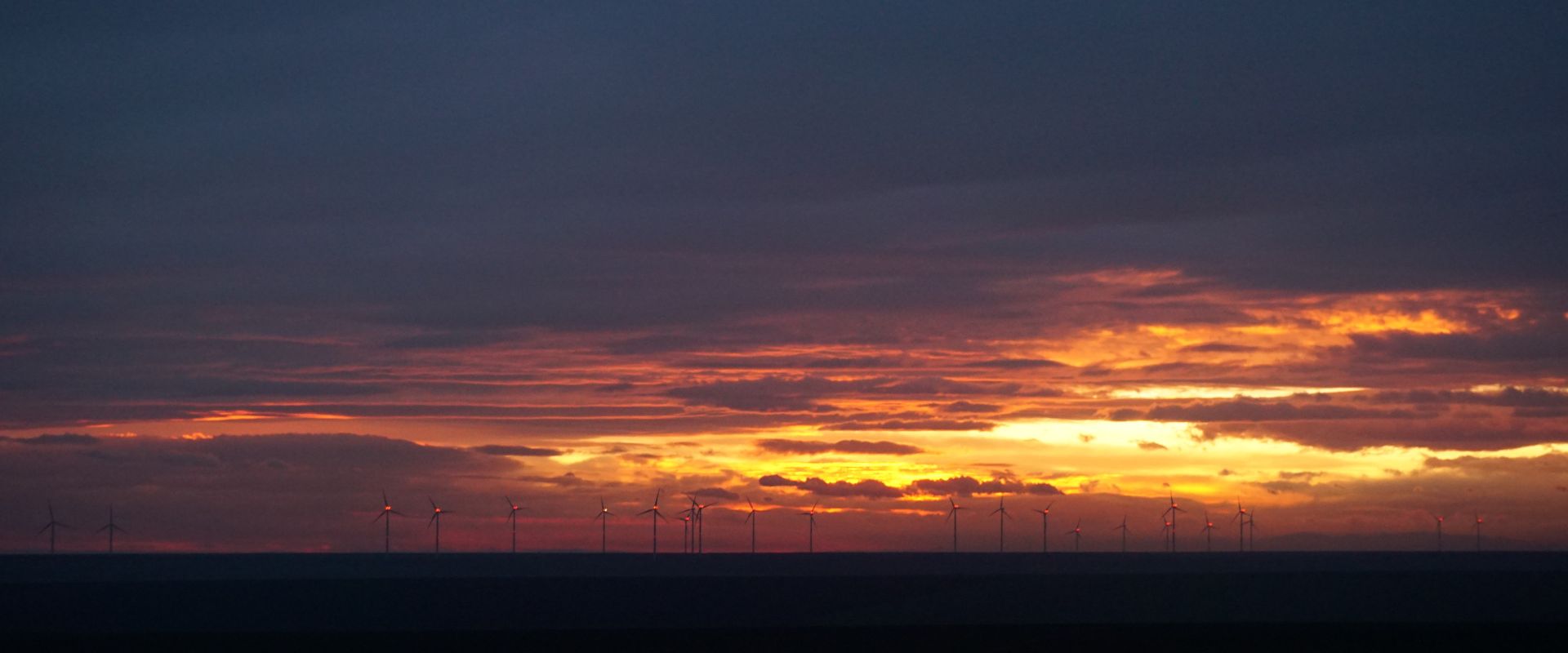 Wind turbines over Romanian farmland at sunset